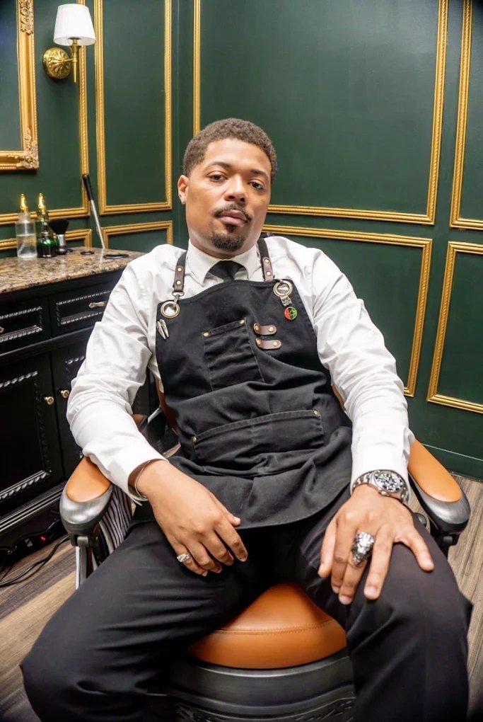 Master barber Darius Tuff seated in a cognac leather barber chair