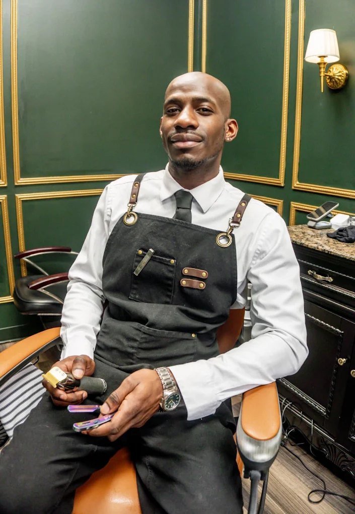 Barber Kevin Black seated in the barber chair holding his clippers