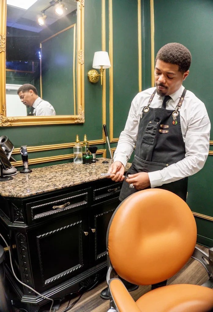 Barber Darius Tuff preparing his tools at a carved black vanity in the green and gold suite